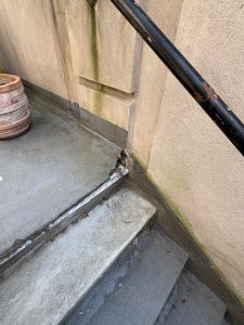 Beskadiget samling og revner ved udendørs trappe før renovering og overfladebehandling